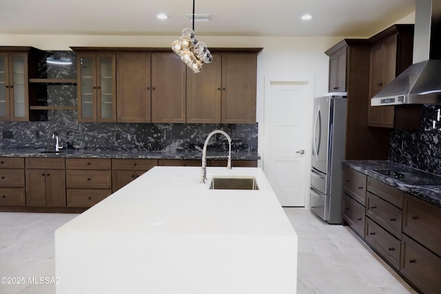 kitchen with wall chimney range hood, a sink, freestanding refrigerator, and black electric cooktop