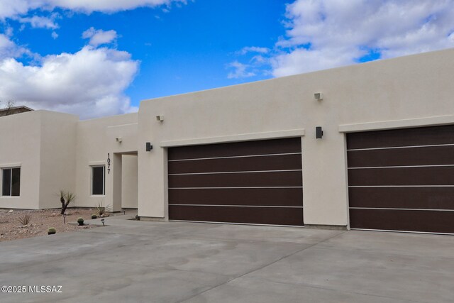 pueblo revival-style home featuring concrete driveway, stucco siding, and an attached garage