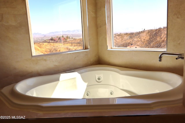 full bathroom with a tub with jets, a wealth of natural light, and a mountain view