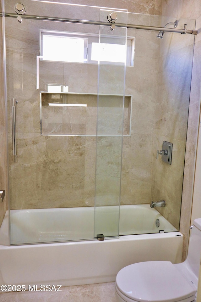 bathroom featuring toilet and bath / shower combo with glass door