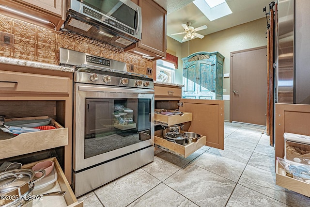 kitchen featuring light countertops, appliances with stainless steel finishes, a skylight, and a ceiling fan