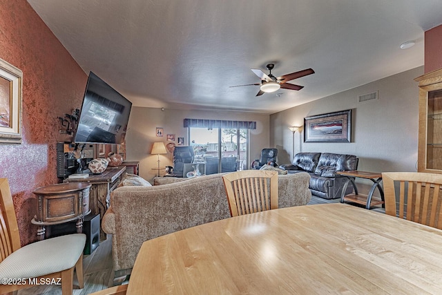 dining space with a ceiling fan, visible vents, and wood finished floors