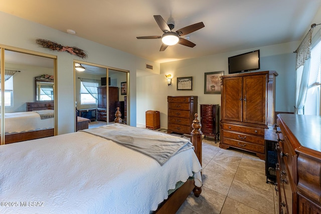 bedroom featuring multiple closets, visible vents, and a ceiling fan