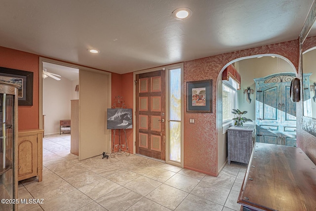 entryway with arched walkways, light tile patterned floors, and recessed lighting