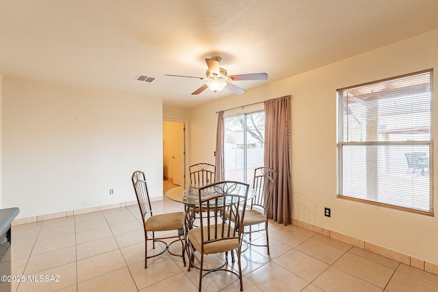 dining area featuring a ceiling fan, light tile patterned flooring, visible vents, and baseboards