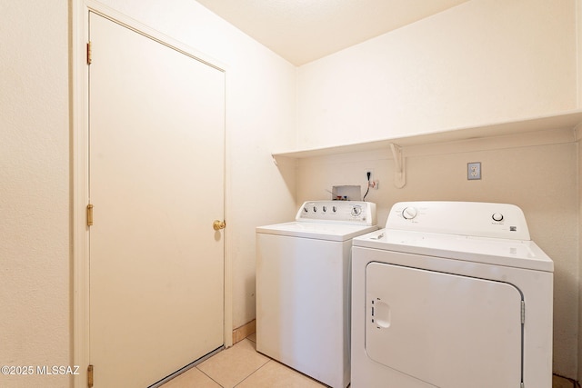 washroom featuring washer and dryer, laundry area, and light tile patterned floors