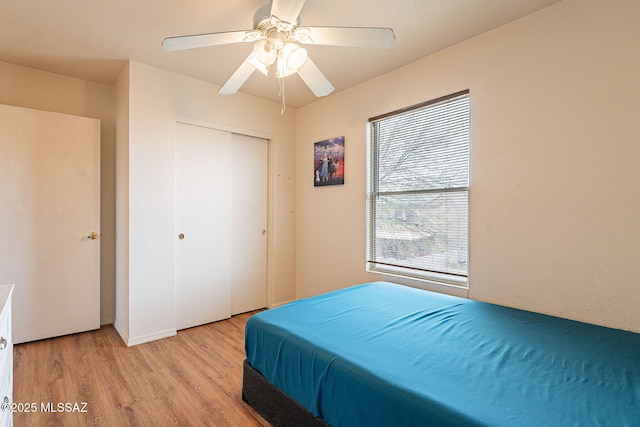 bedroom featuring ceiling fan, a closet, and light wood-style flooring