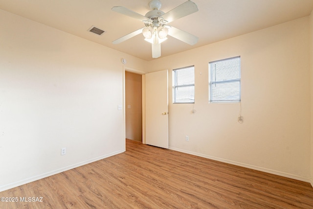 spare room featuring light wood-type flooring, visible vents, ceiling fan, and baseboards