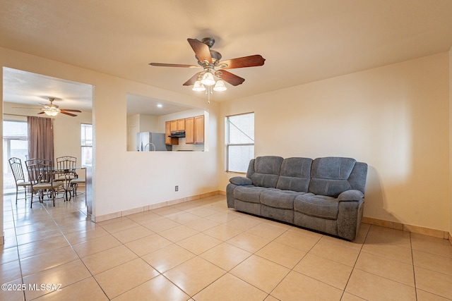 living area featuring a ceiling fan, baseboards, and light tile patterned floors