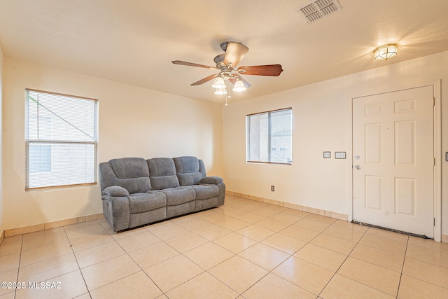 living area with light tile patterned floors, baseboards, visible vents, and a ceiling fan