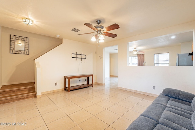 living room featuring a ceiling fan, visible vents, baseboards, and light tile patterned floors