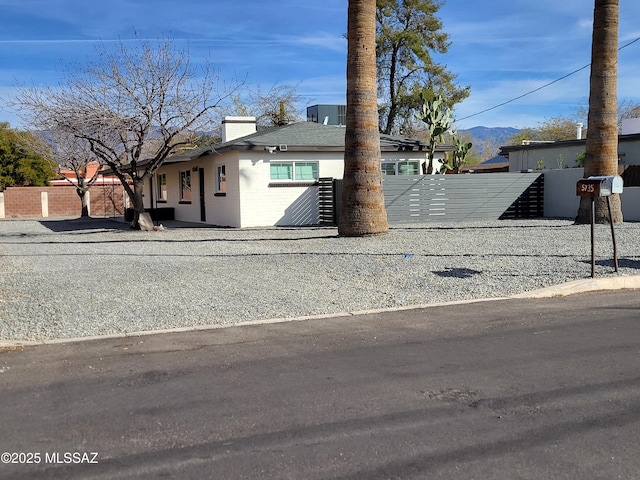 view of front of property featuring concrete block siding, fence, a chimney, and a mountain view