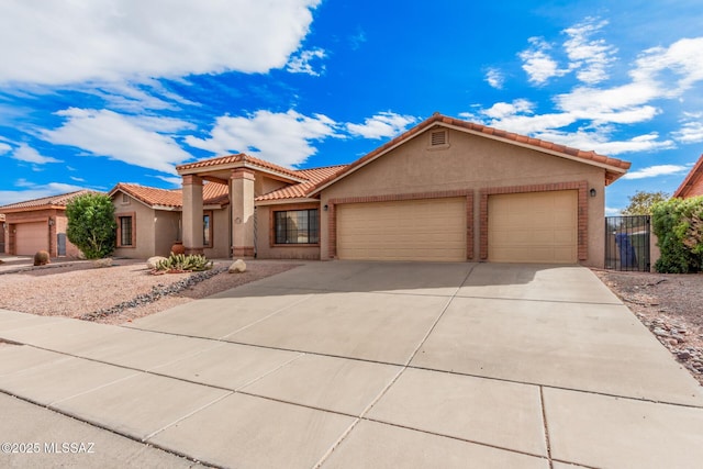 mediterranean / spanish house featuring concrete driveway, an attached garage, a tile roof, and stucco siding