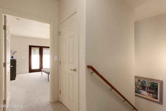 corridor with light carpet and an upstairs landing