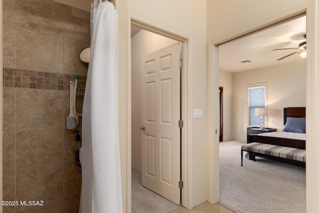 interior space featuring tiled shower, ensuite bath, and a ceiling fan