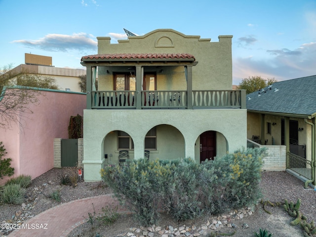 mediterranean / spanish house with a tiled roof, a balcony, and stucco siding