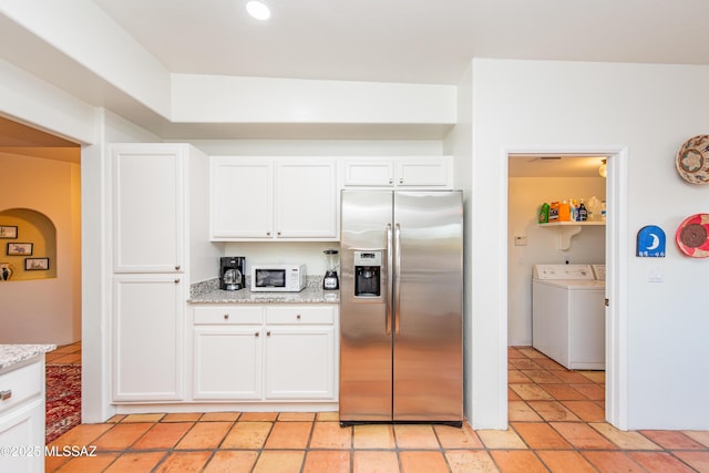 kitchen with stainless steel fridge, white microwave, light stone countertops, washer and dryer, and white cabinetry