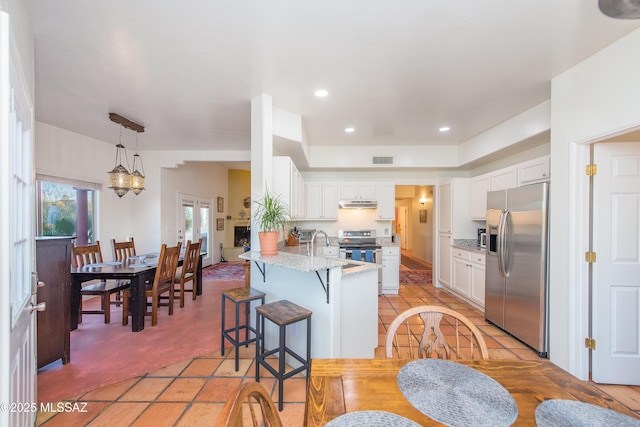 kitchen featuring visible vents, a peninsula, stainless steel appliances, under cabinet range hood, and white cabinetry