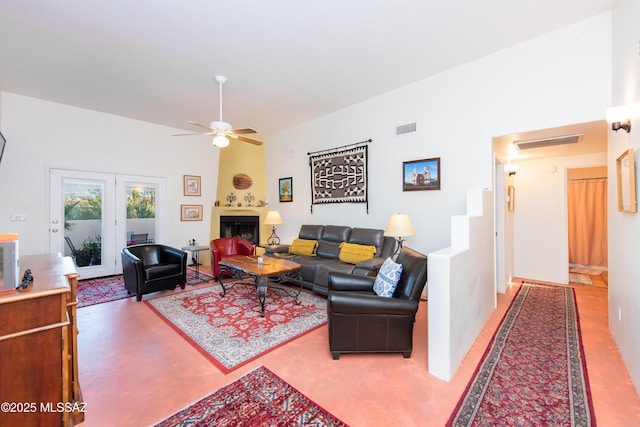 living room featuring a ceiling fan, visible vents, a fireplace, and a towering ceiling