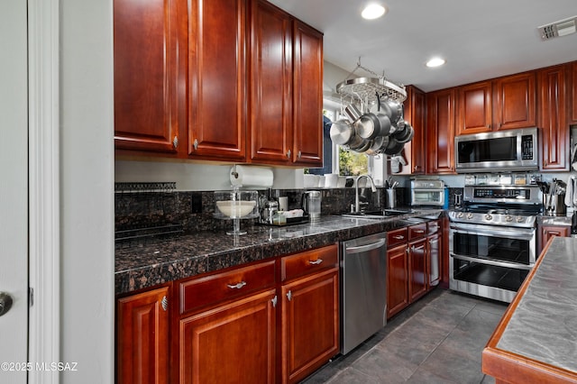 kitchen featuring reddish brown cabinets, visible vents, tile countertops, appliances with stainless steel finishes, and a sink