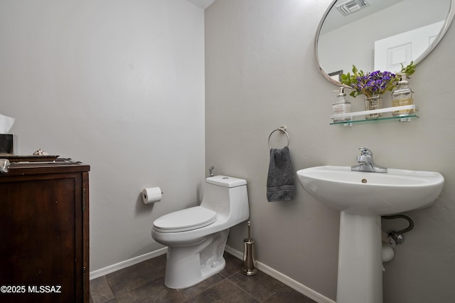 half bath with toilet, tile patterned flooring, visible vents, and baseboards