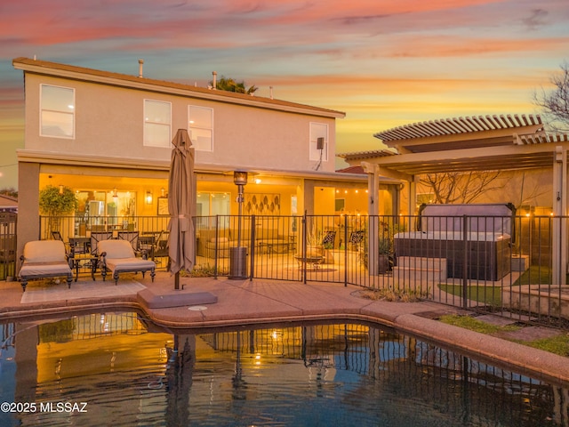 back of property at dusk featuring a patio, fence, and stucco siding