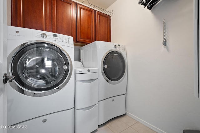 laundry room with cabinet space, independent washer and dryer, baseboards, and light tile patterned flooring