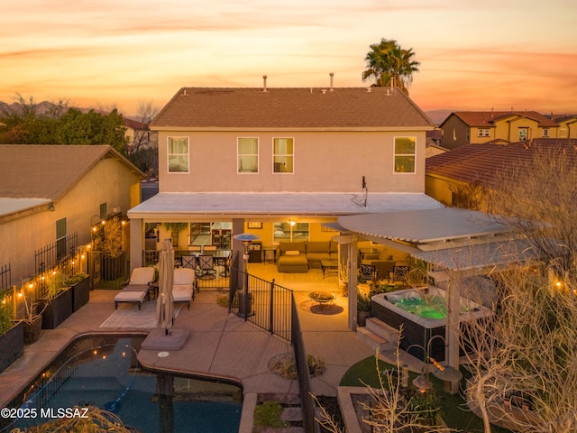 back of house at dusk featuring a fire pit, a patio, a fenced in pool, and a hot tub