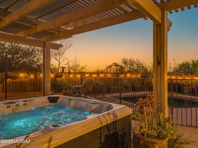 pool at dusk featuring fence, a hot tub, and a pergola