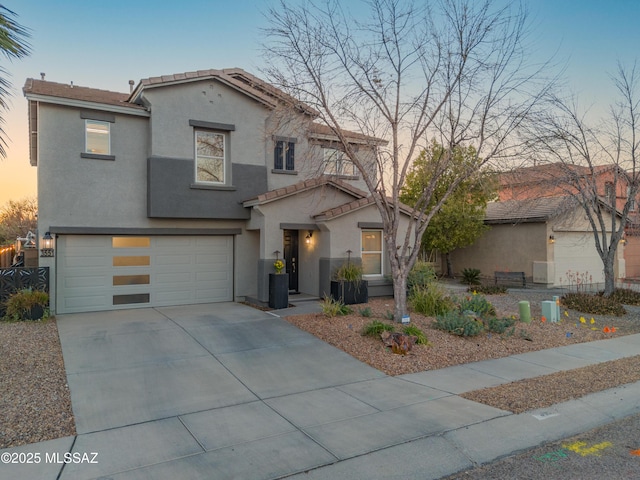 view of front facade featuring driveway, a tiled roof, a garage, and stucco siding