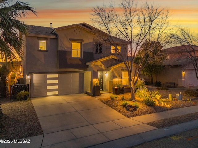 mediterranean / spanish house with driveway, an attached garage, a tile roof, and stucco siding