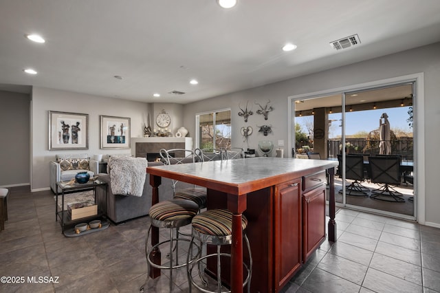 kitchen featuring a fireplace, visible vents, dark brown cabinets, and recessed lighting