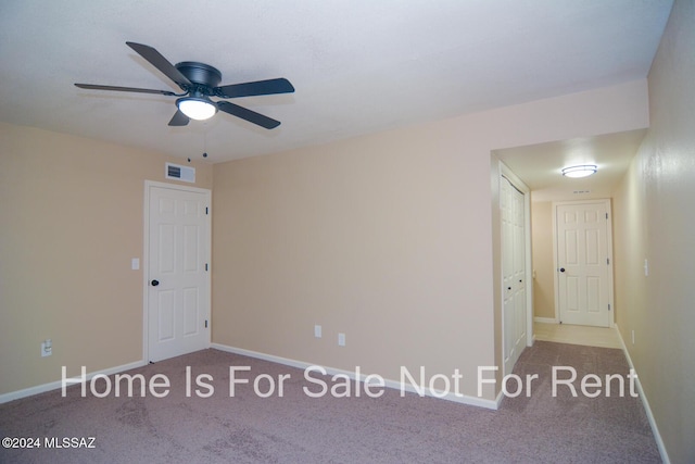 empty room featuring carpet floors, visible vents, ceiling fan, and baseboards