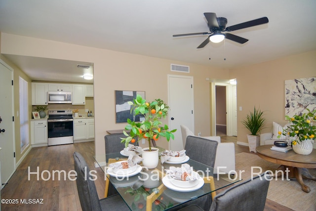 dining room with dark wood-style floors, visible vents, and ceiling fan