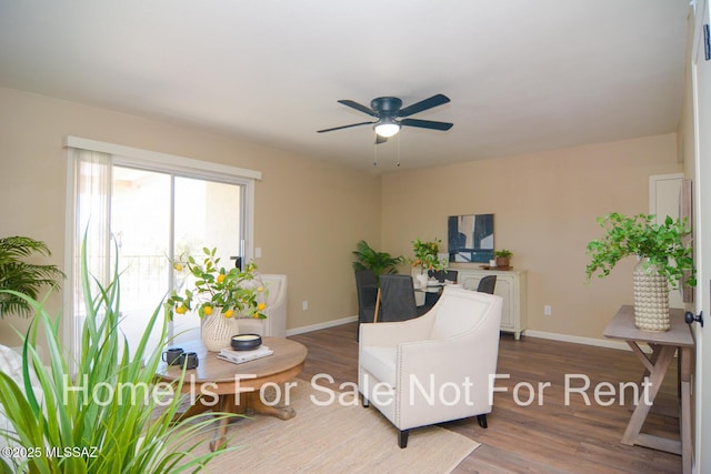 sitting room with a ceiling fan, baseboards, and wood finished floors