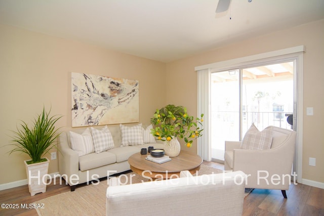 living area featuring ceiling fan, baseboards, and wood finished floors