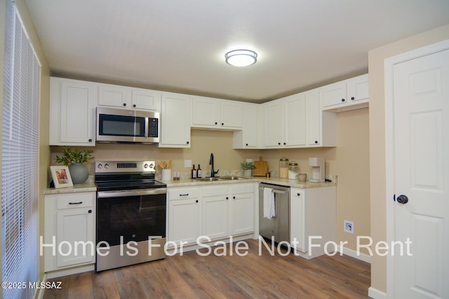 kitchen featuring dark wood-style floors, stainless steel appliances, a sink, and white cabinetry