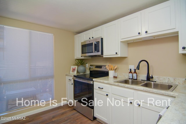 kitchen with a sink, stainless steel appliances, light countertops, and white cabinetry