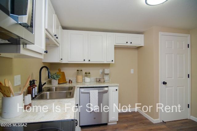 kitchen featuring baseboards, white cabinetry, stainless steel appliances, and a sink