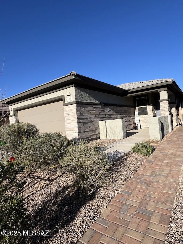 view of home's exterior featuring an attached garage, stone siding, and stucco siding