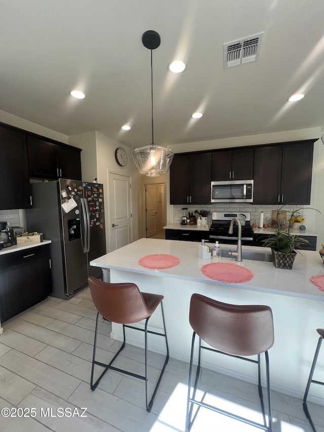 kitchen with a breakfast bar, visible vents, light countertops, appliances with stainless steel finishes, and backsplash