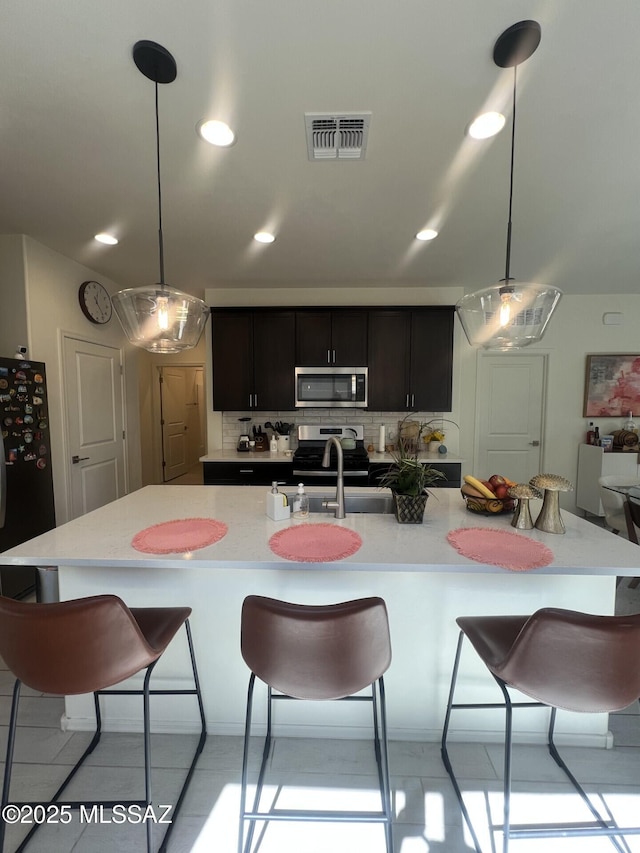 kitchen with visible vents, appliances with stainless steel finishes, a kitchen breakfast bar, and light countertops