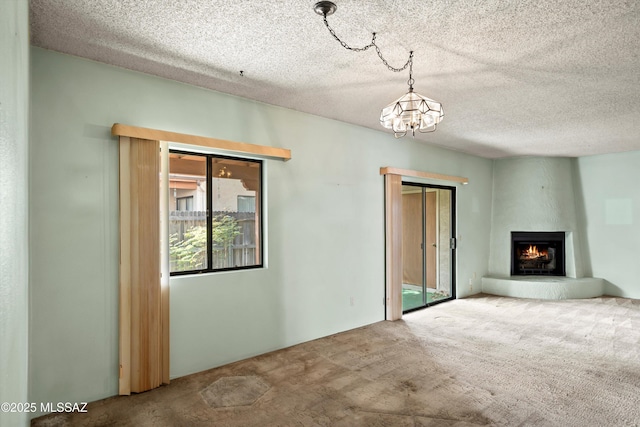 unfurnished living room with a chandelier, a large fireplace, carpet flooring, and a textured ceiling