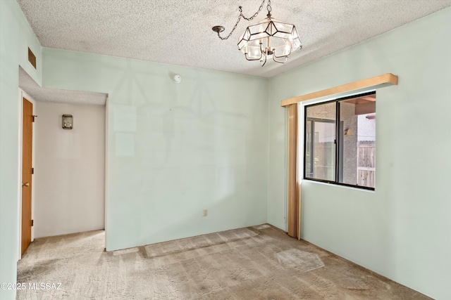 carpeted spare room with a notable chandelier, visible vents, and a textured ceiling