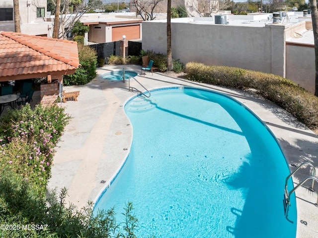 pool featuring a patio area, fence, and a hot tub