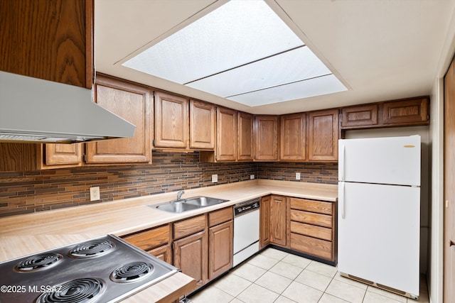 kitchen with light tile patterned floors, white appliances, a sink, light countertops, and backsplash