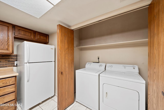 clothes washing area with laundry area, washer and clothes dryer, and light tile patterned flooring