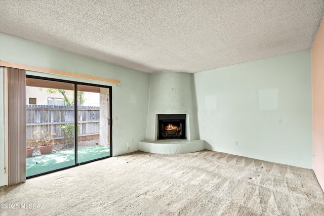 unfurnished living room featuring carpet floors, a large fireplace, and a textured ceiling