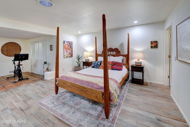 bedroom with baseboards, a textured ceiling, wood finished floors, and recessed lighting