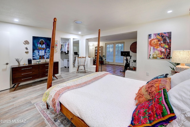 bedroom featuring access to outside, a spacious closet, french doors, light wood-type flooring, and recessed lighting